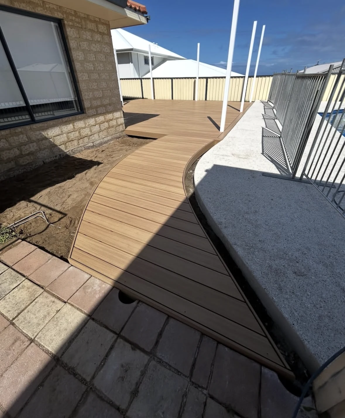 A curved poolside deck follows the edge of a swimming pool in Bunbury